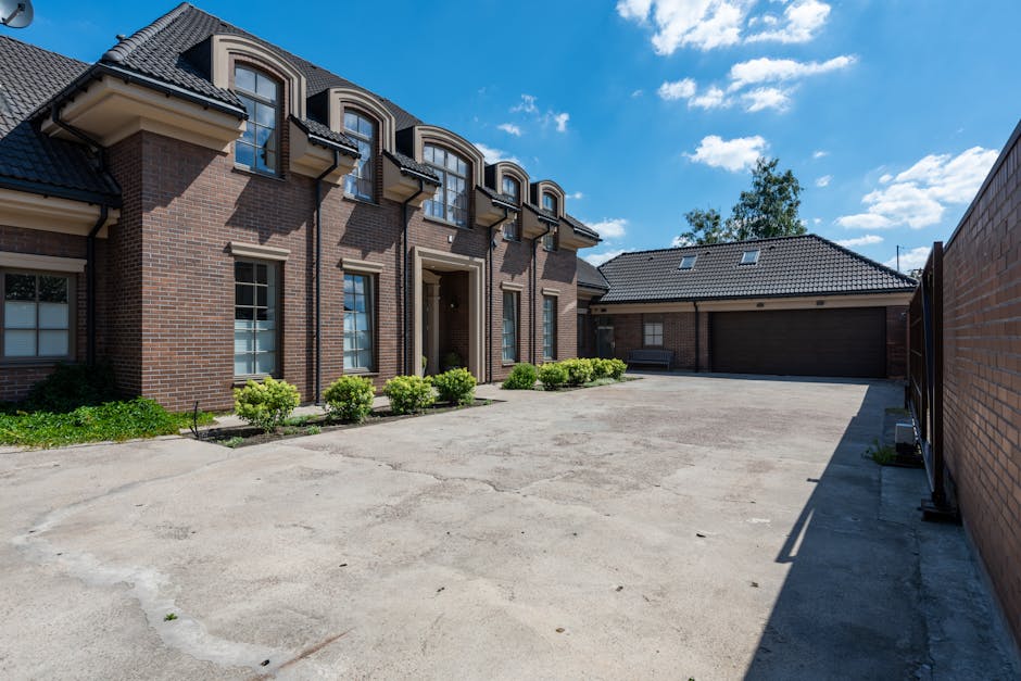 Elegant brick house exterior with a large driveway under a clear blue sky.